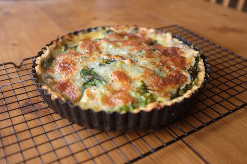 A pea and leek tart cooling on a cooling rack.