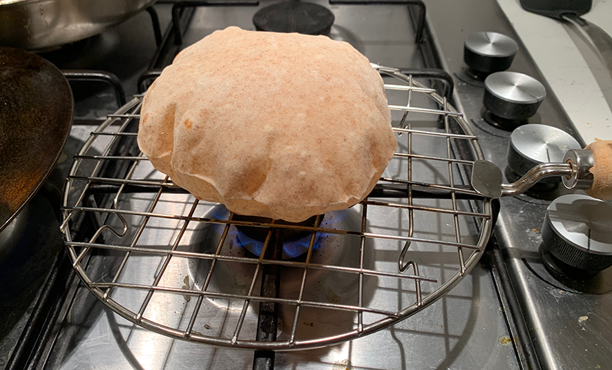 An image of a chapati that has fully inflated over a naked flame.