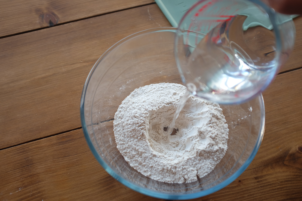 Water being combined with flour in a mixing bowl.