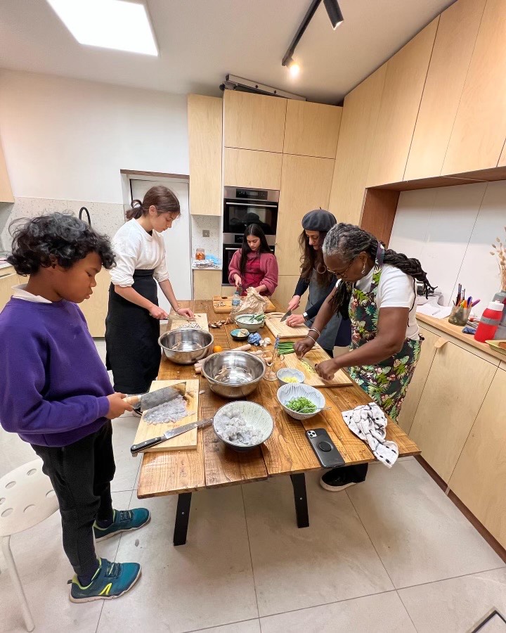 Several people in a kitchen making dumplings.