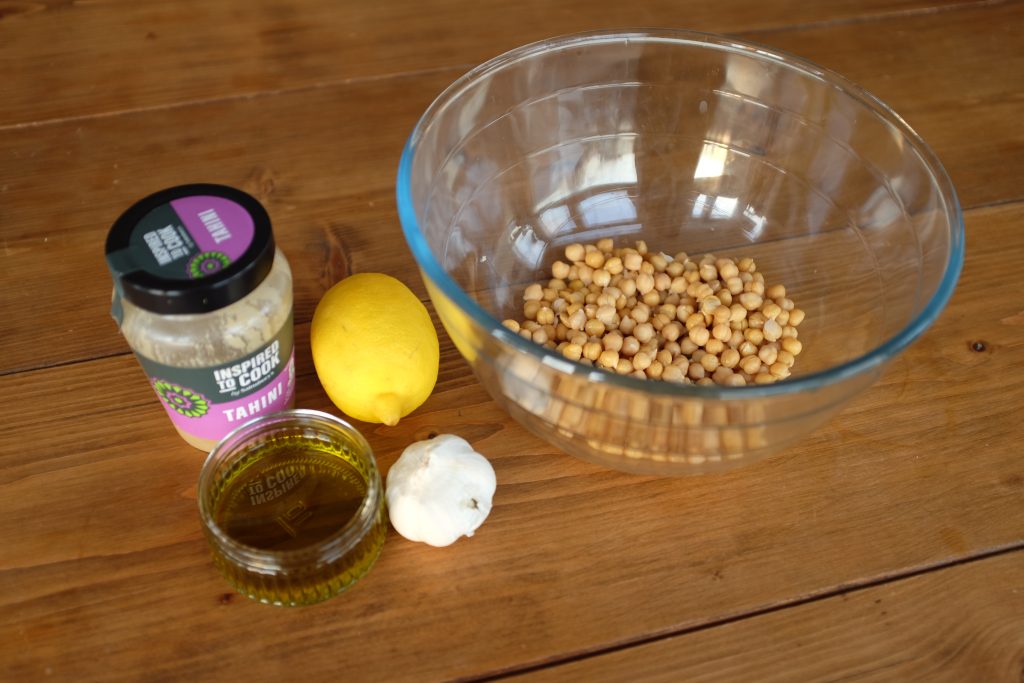 All the ingredients you need for hummus: tahini, chickpeas, olive oil, garlic, and lemon.