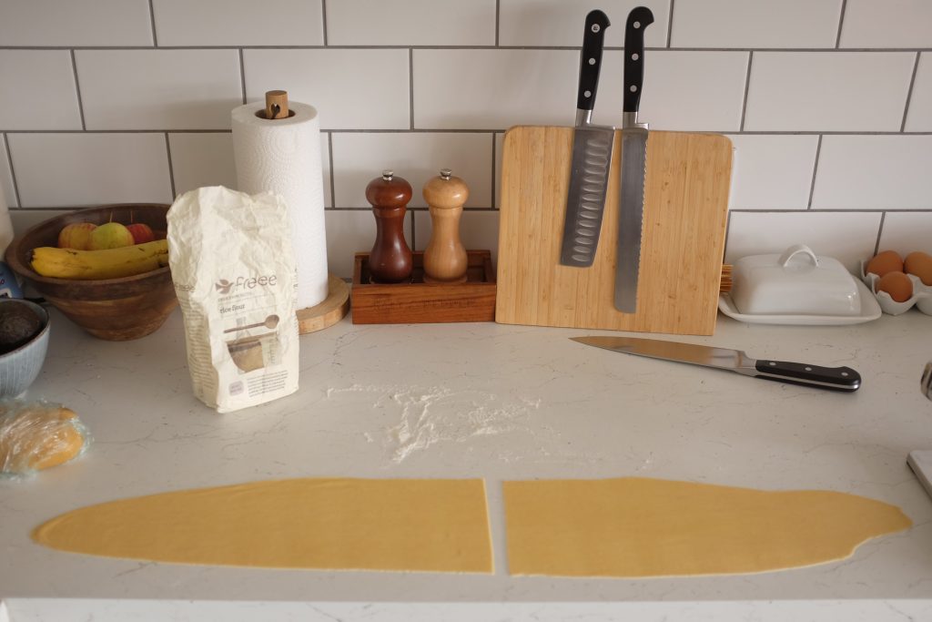 A sheet of pasta cut in half on a work surface.