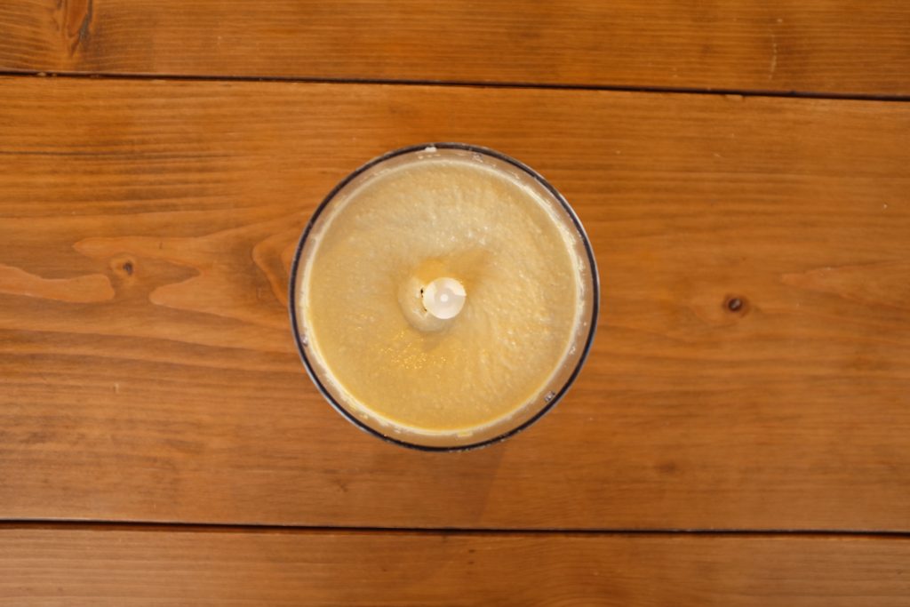 A food processor with freshly blended hummus.