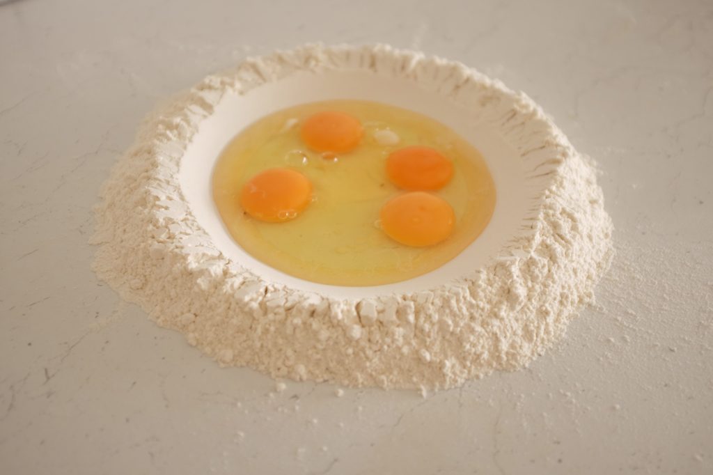 Eggs cracked into a well of flour.