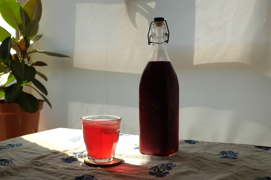 A bottle of fruit squash next to a glass